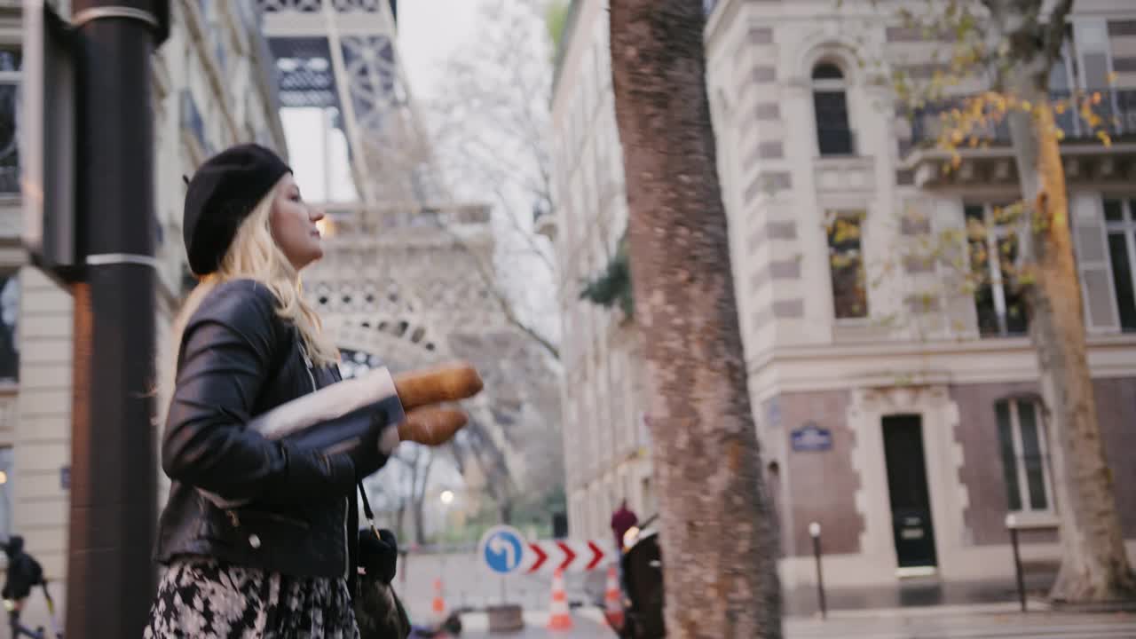 时尚的法国女人沿着艾菲尔铁塔走在街上，手里拿着长棍面包视频下载