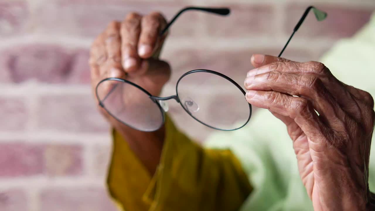年长妇女手拿旧眼镜的特写视频下载