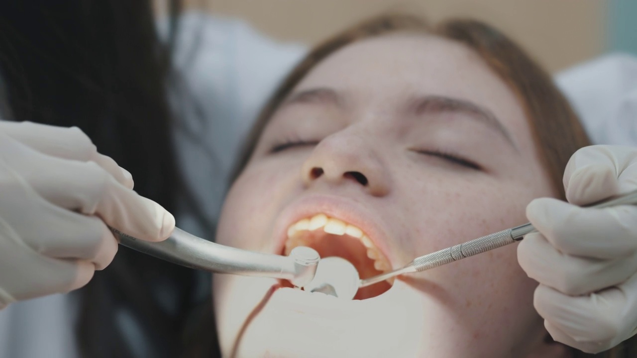 十几岁的女孩在牙医那里检查牙齿。可爱的女孩坐在牙科椅上接受牙科治疗。视频素材