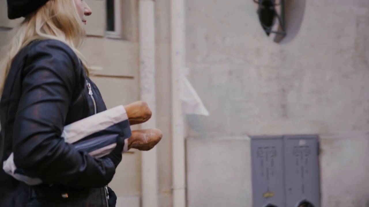 迷人的法国女人在巴黎的大街上拿着长棍面包视频素材
