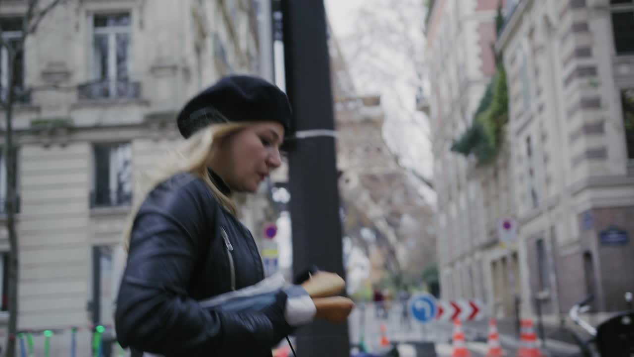 时尚的法国女人一边走在艾菲尔铁塔旁的大街上，一边吃着法棍面包视频素材