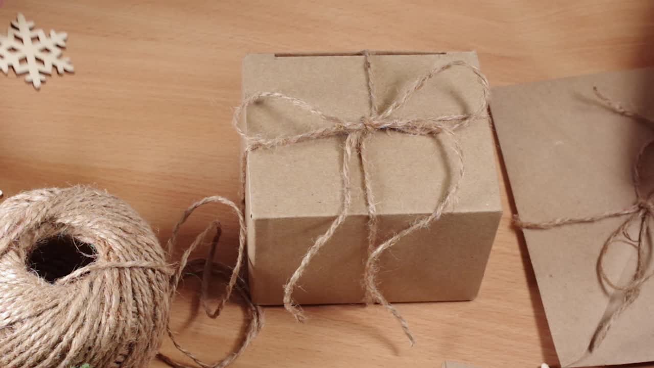 环保礼物，自制礼物，DIY。手附木制雪花牛皮纸盒与绳弓在桌子上。为圣诞节装饰礼品盒。“零浪费”的概念视频下载
