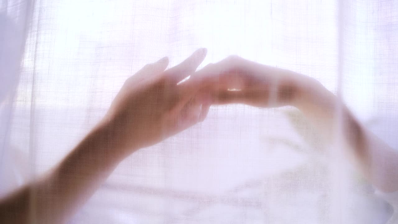 妩媚的女人躲在透明的窗帘后面。手之舞视频素材