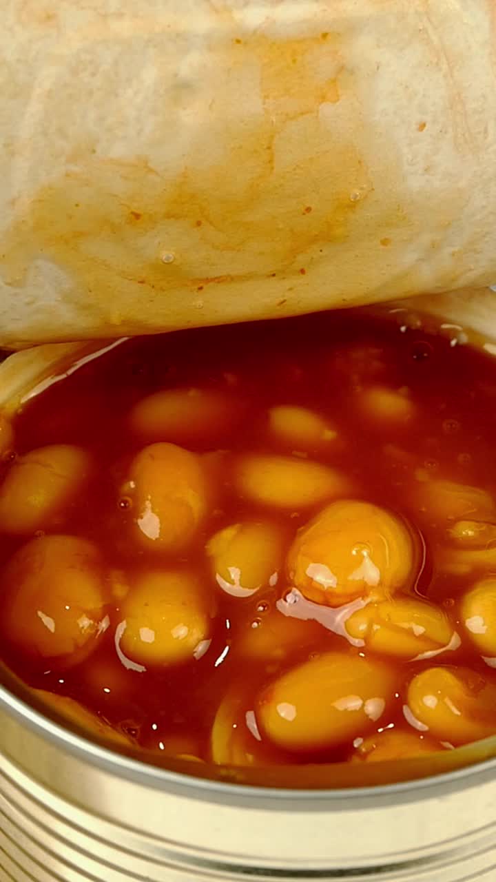 勺子从金属罐头里取出番茄酱炖豆。视频素材