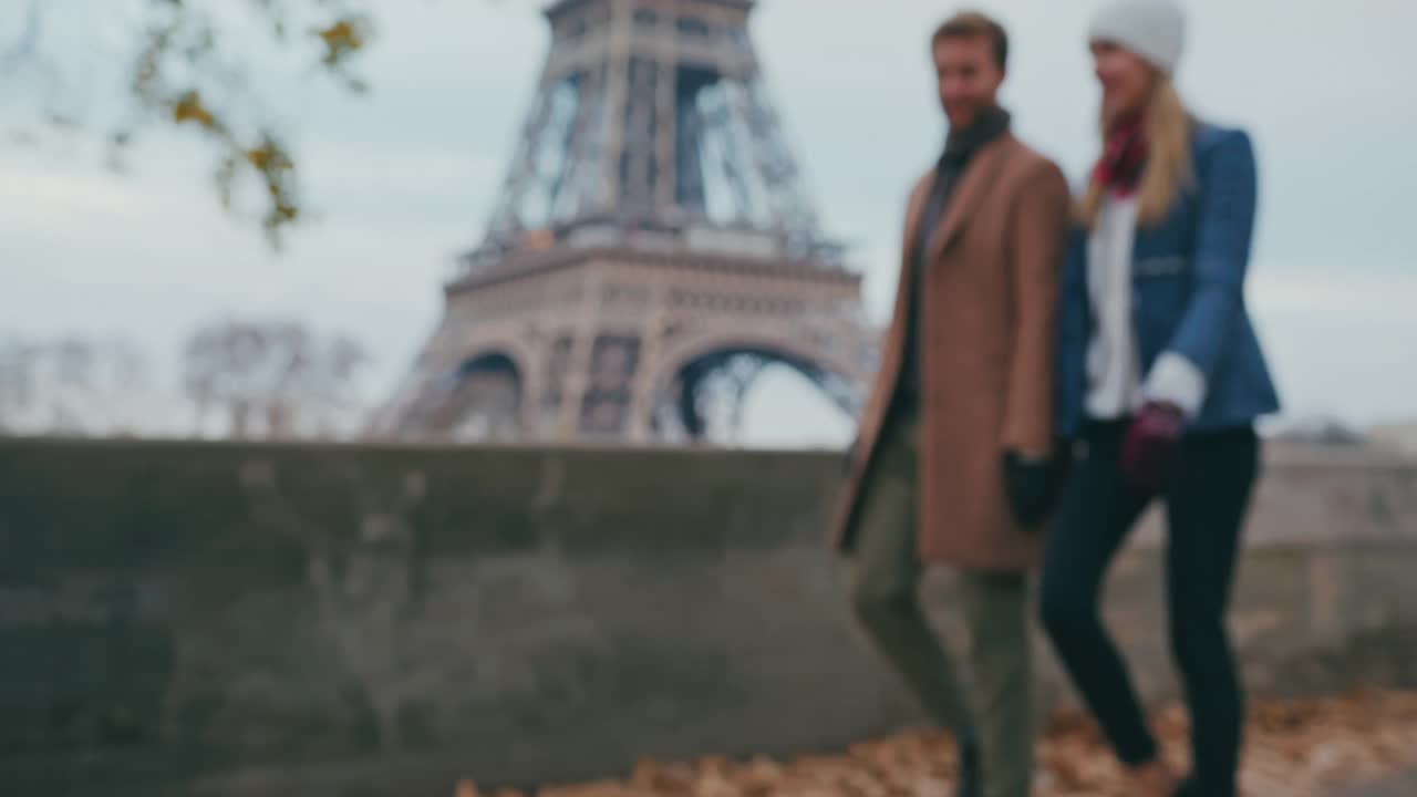一对年轻的情侣沿着艾菲尔铁塔走在人行道上视频下载