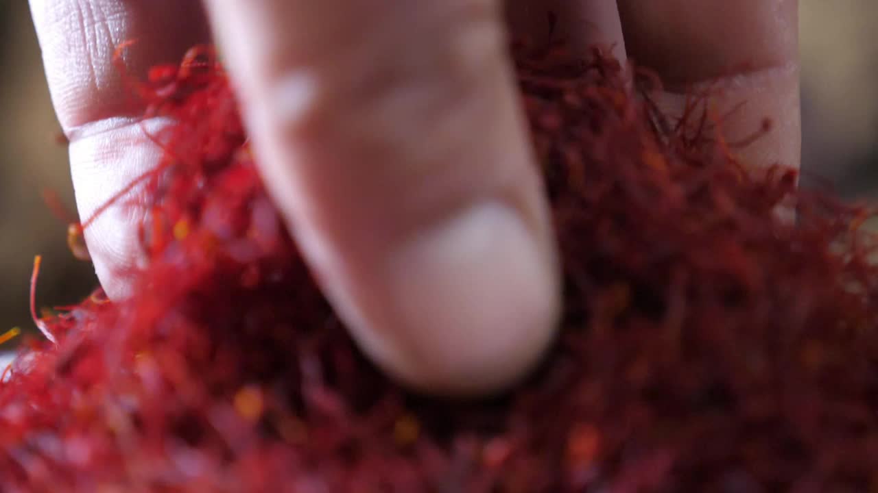 人的手拿着磨碎的藏红花香料让它缓缓落下细细的条纹视频下载