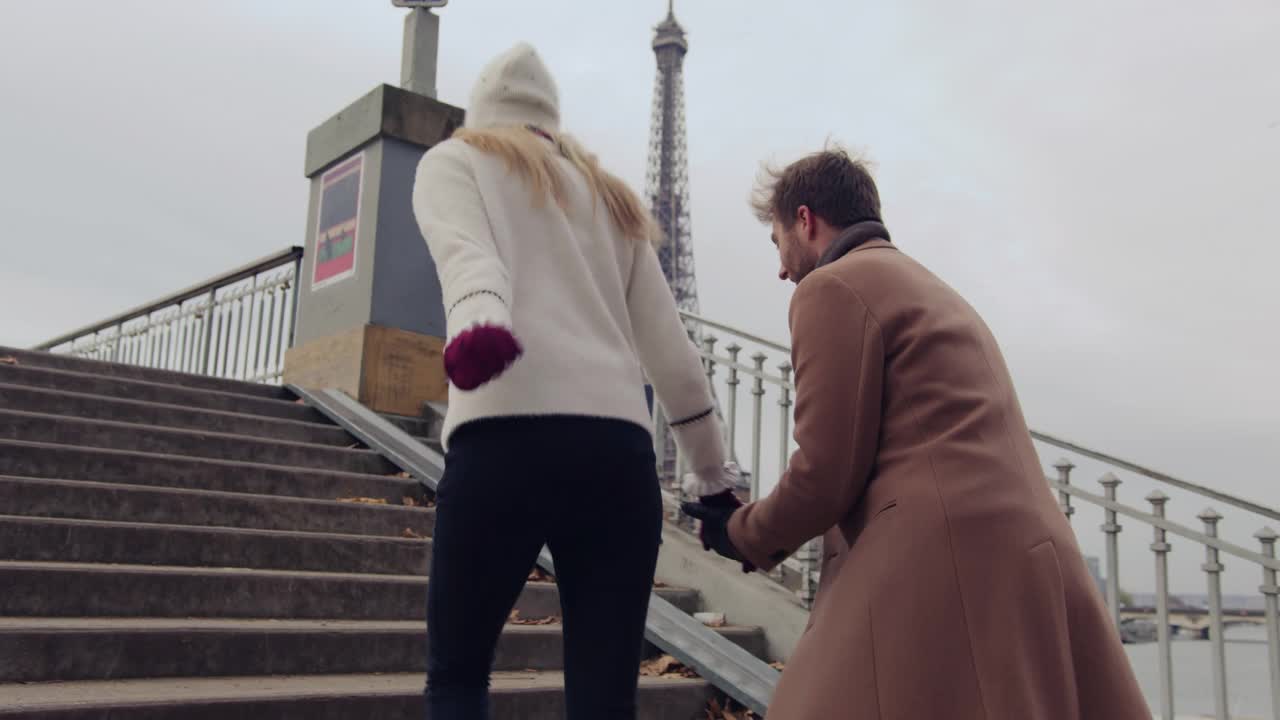 这对恩爱情侣在埃菲尔铁塔旁塞纳河上一座桥的楼梯上奔跑视频素材
