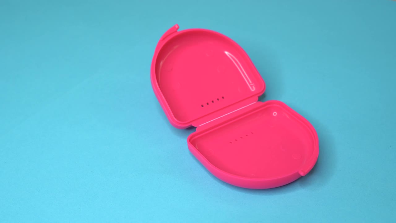 医生从一个粉红色的盒子里拿出一个牙固定器或牙夹板视频下载