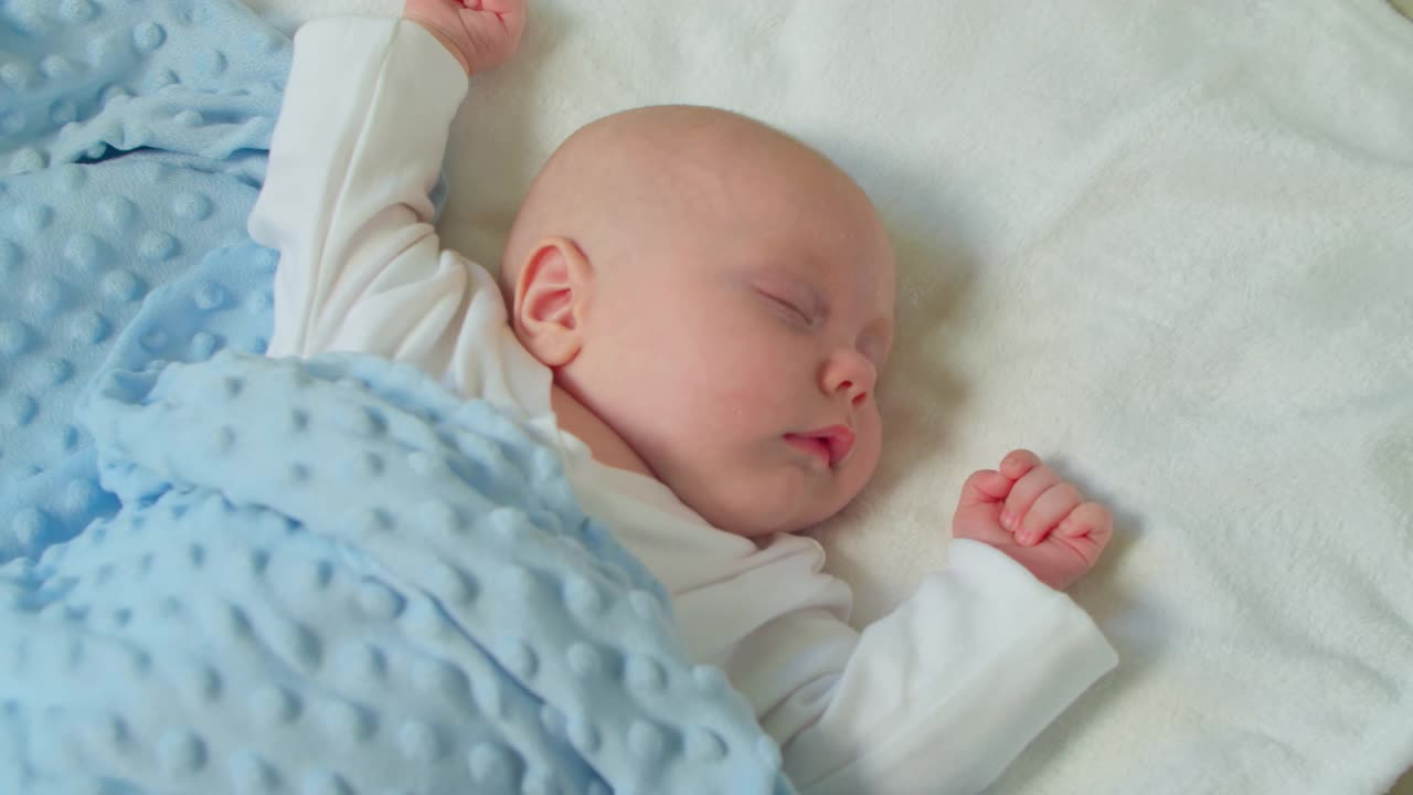 新生婴儿睡在家里房间的床上。一个熟睡的孩子的概念。男孩在家里睡觉，看着梦视频素材
