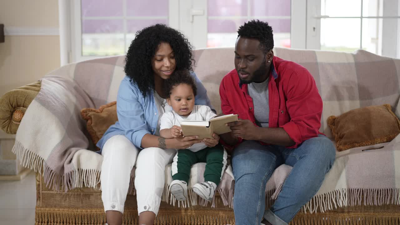 肖像古玩可爱的小男孩听夫妇父母读童话故事。快乐的非洲裔美国幼儿享受周末休闲与快乐的聪明的父亲和母亲。视频素材