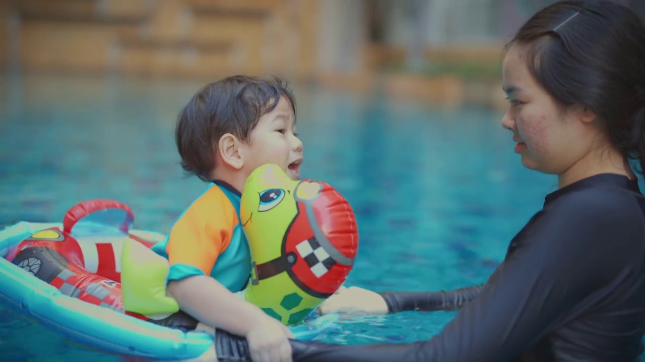 照顾孩子，一个女孩和她的弟弟穿着游泳在游泳池里。视频下载