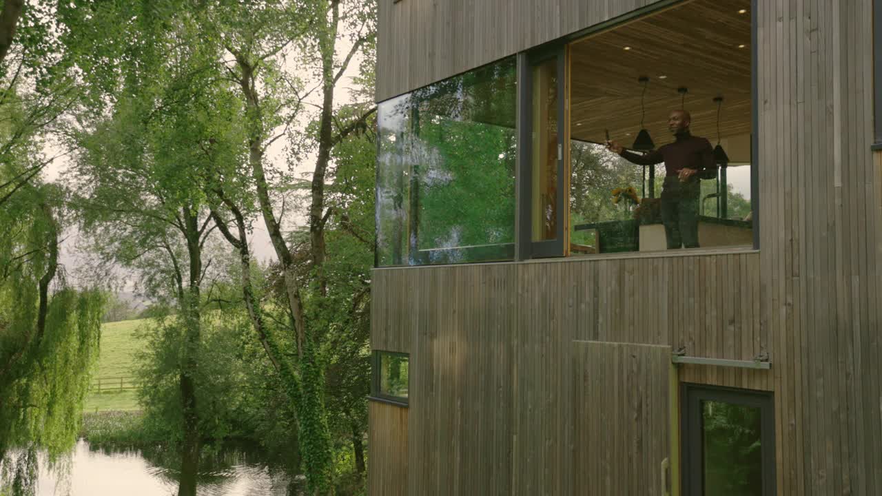 一对夫妇在英国德文郡蒂弗顿现代住宅的窗户里看视频素材
