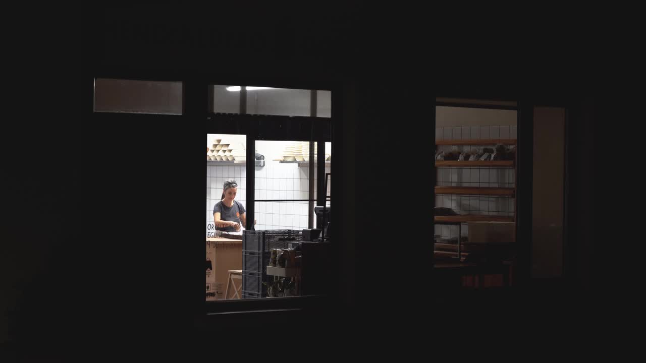 从黑暗的外面可以看到女面包师在工作视频下载