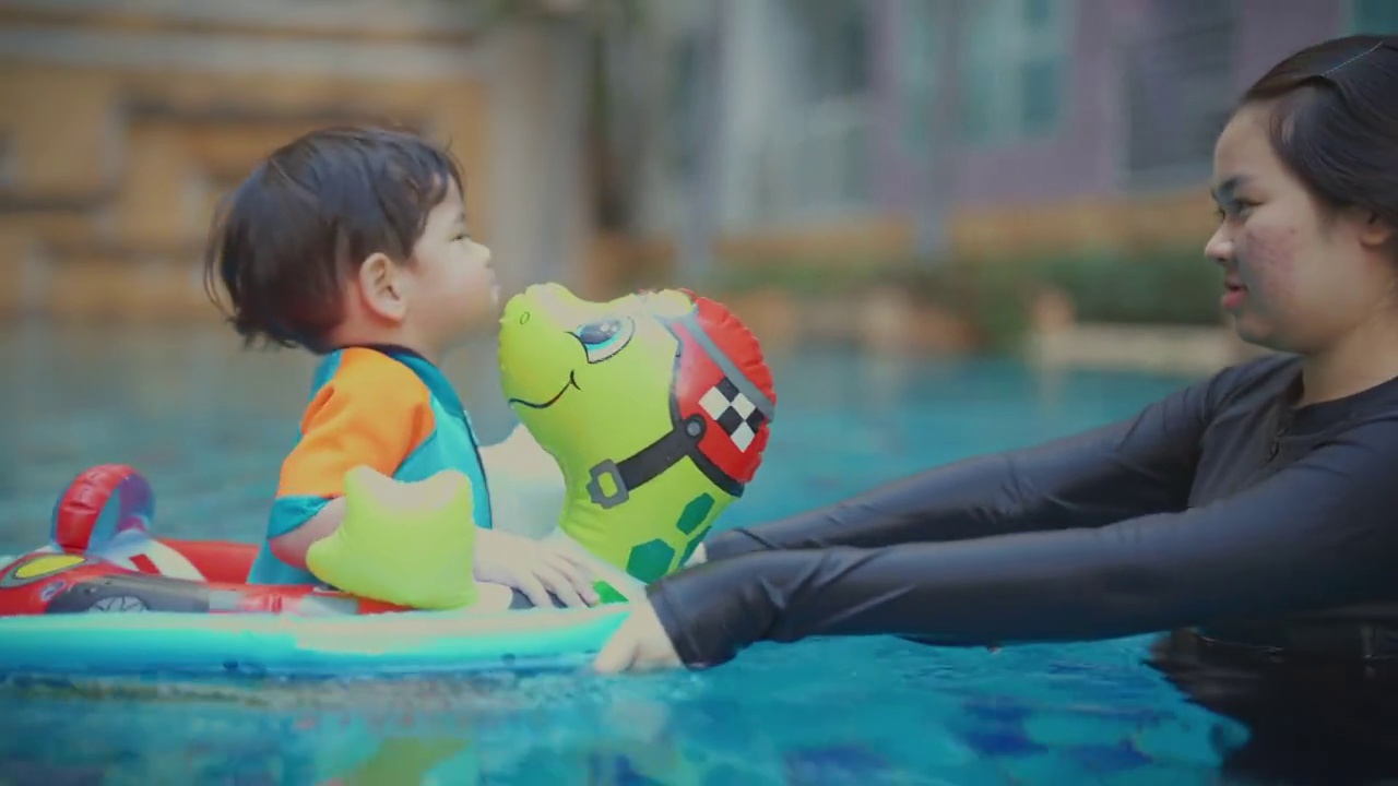 照顾孩子，一个女孩和她的弟弟穿着游泳在游泳池里。视频下载