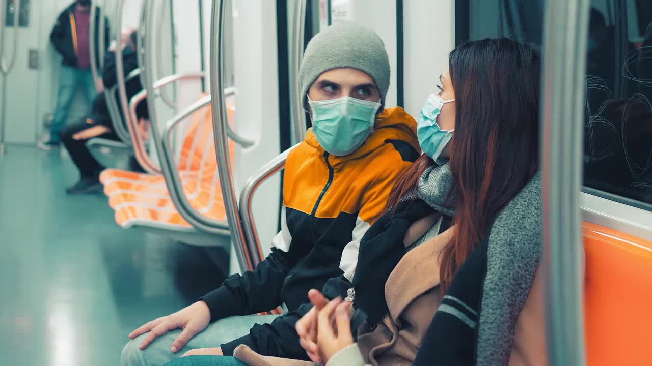 疫情期间的公共交通——年轻夫妇戴着口罩乘坐地铁视频下载