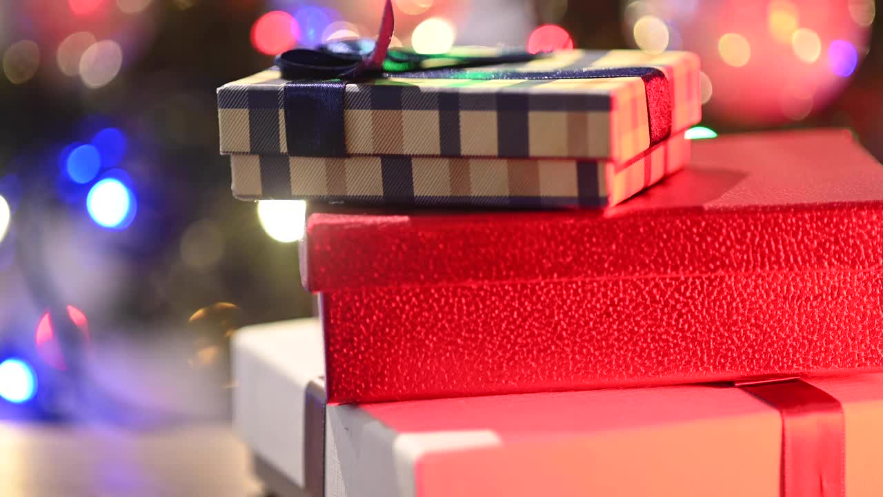 三个圣诞礼物。背景是一棵装饰好的圣诞树。视频下载