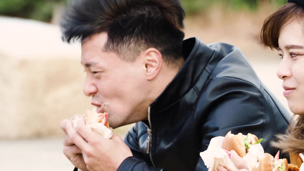 男男女女坐在公园里吃汉堡。视频下载