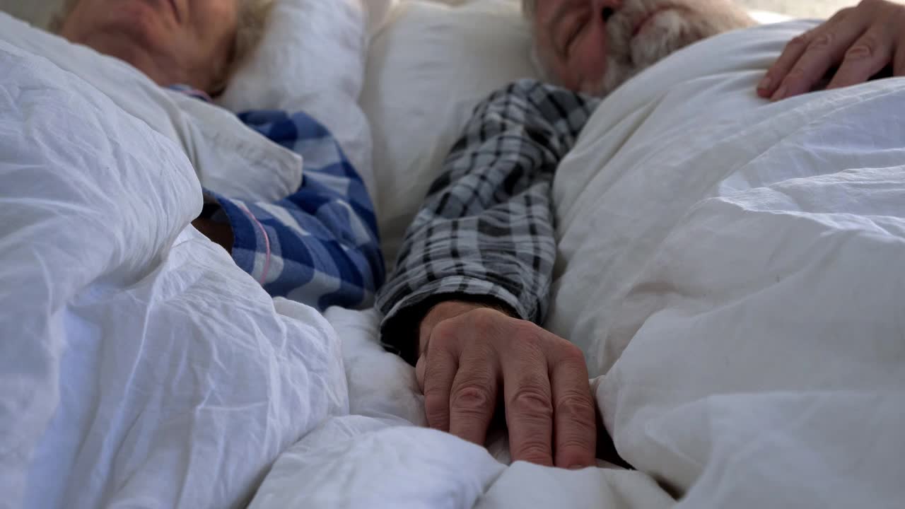 老夫妇手牵着手躺在床上视频素材