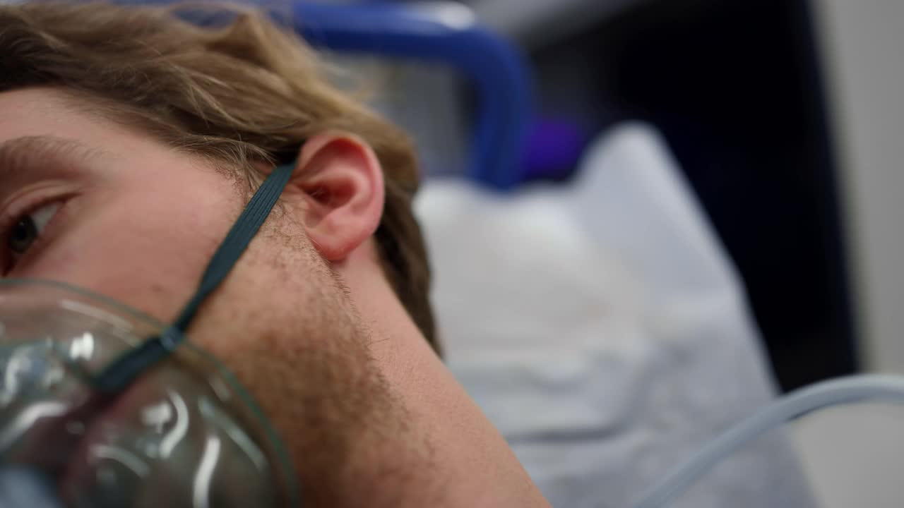 伤者戴着氧气面罩躺在救护车的担架上视频下载