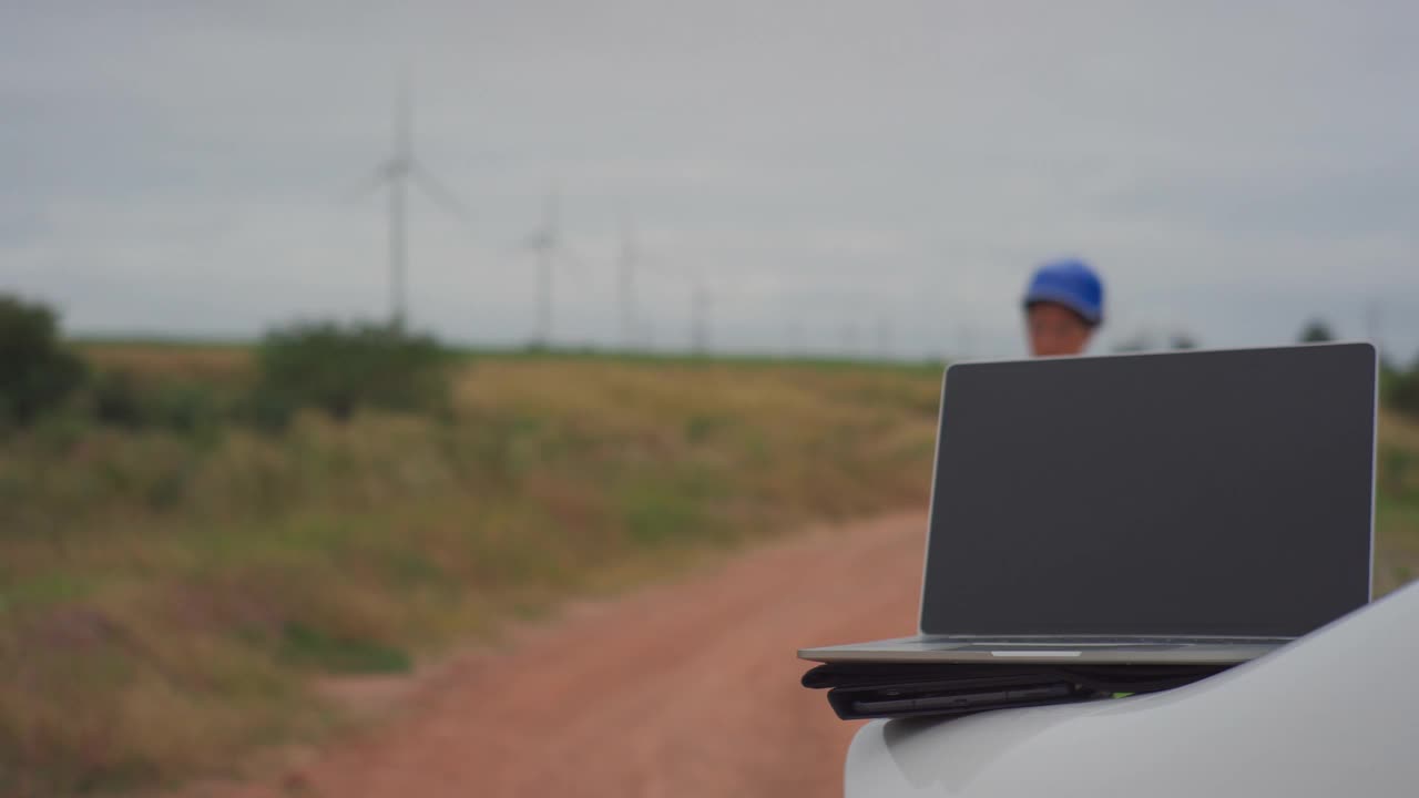 女性工程师使用智能手机在风力涡轮机农场工作的视频。视频素材