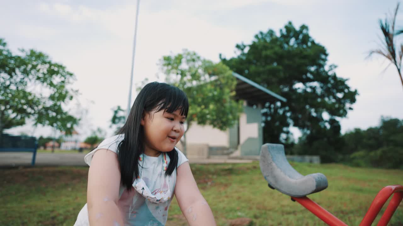 亚洲小女孩正在户外游乐场玩跷跷板视频下载