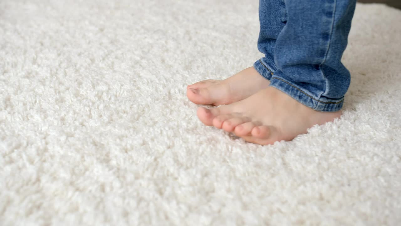 特写的小裸孩子的脚走在柔软的白色地毯上视频下载