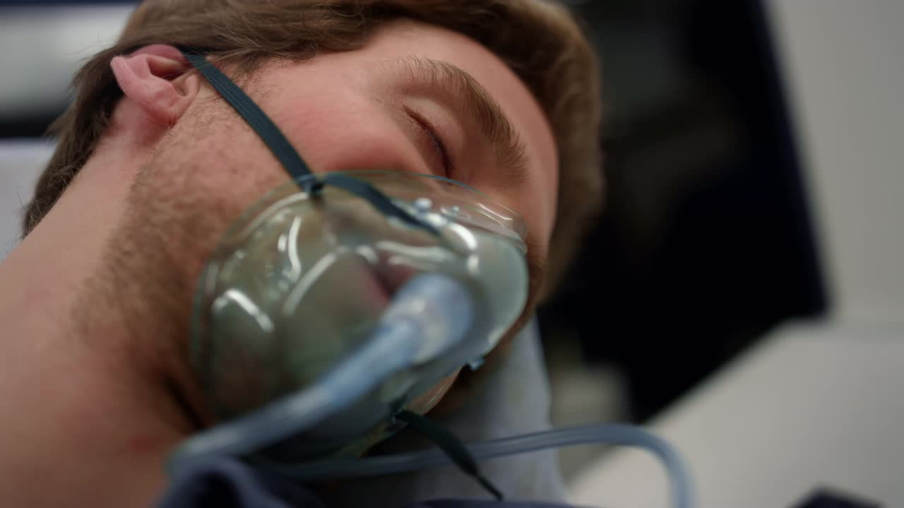 昏迷的人戴着氧气面罩呼吸。躺在担架上的男病人视频素材