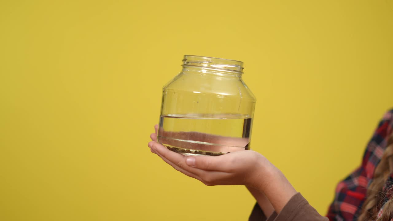 近景水族瓶里的小鲶鱼在无法辨认的十几岁女孩的手中游泳。白人女性青少年活动家在复制空间和鱼在水里。生态系统概念视频下载