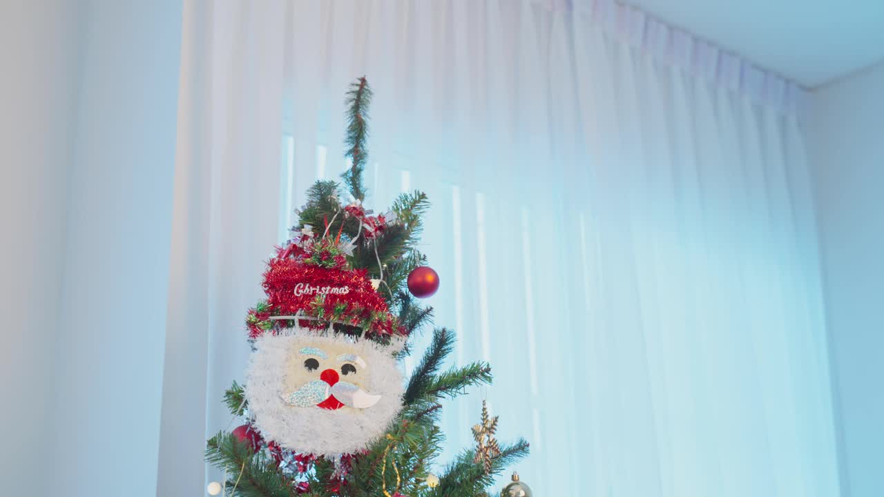 亚洲可爱的家庭，父亲和孩子女儿装饰圣诞树。年幼的女儿兴高采烈地和父母一起在家里庆祝节日圣诞感恩节派对视频素材