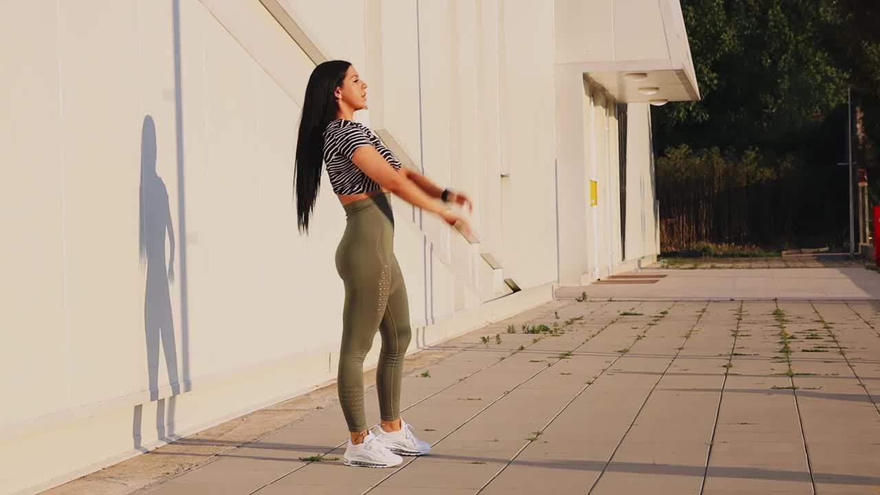 一名女子在阳光明媚的日子里做运动前的热身运动视频下载