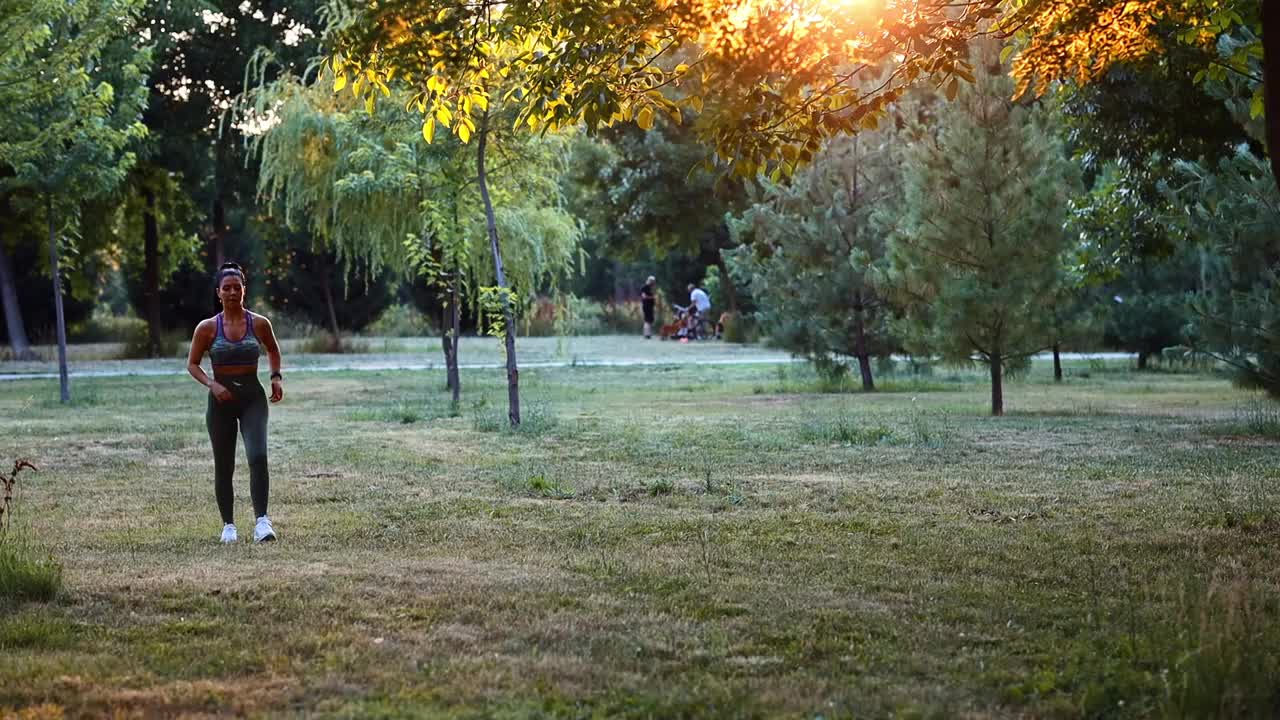 一个阳光明媚的夏日，年轻女子在城市公园跑步视频下载