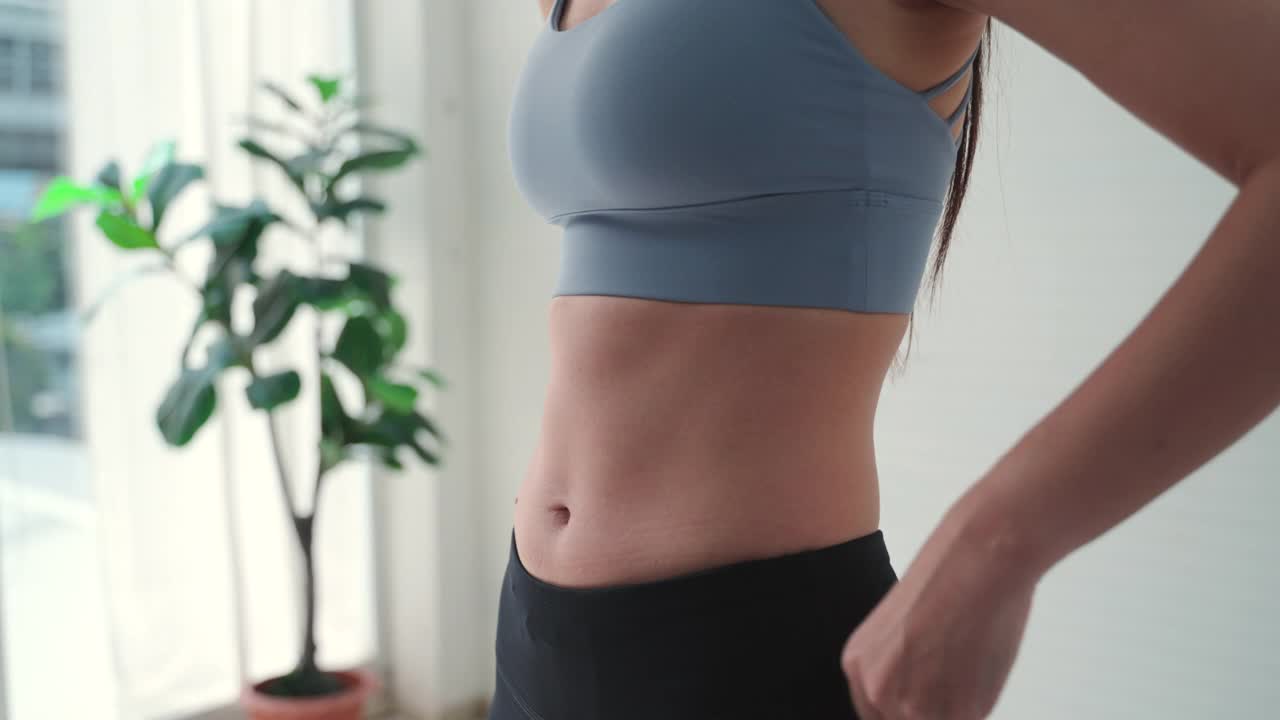 照片中身材苗条的女人正在测量她的腰围和躯干。健康营养和减肥理念。视频下载