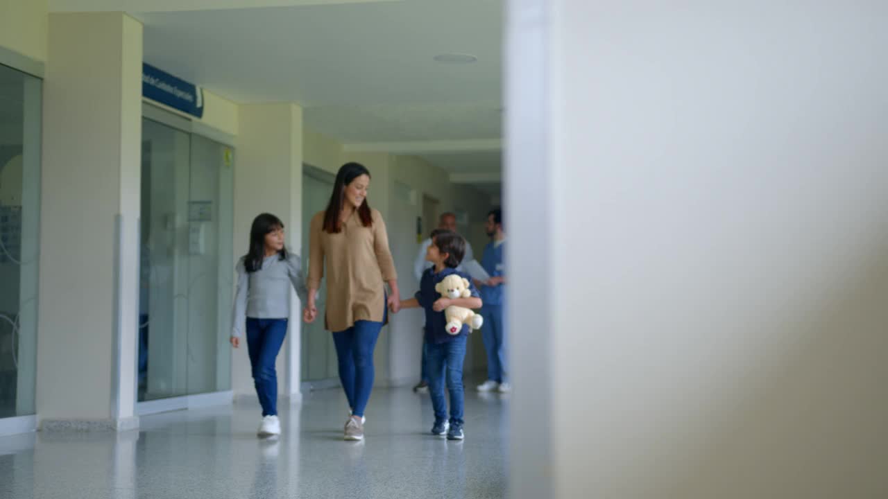单亲妈妈牵着孩子的手，走在医院的走廊上，有说有笑视频素材