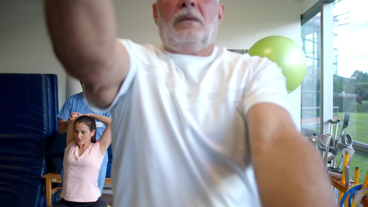 老年男性病人锻炼他的肩膀和手臂与一个环跟随他的治疗师指导视频下载