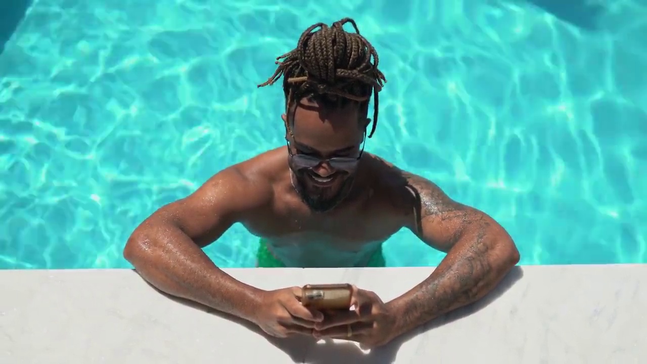 非洲裔男子在泳池里使用智能手机视频素材