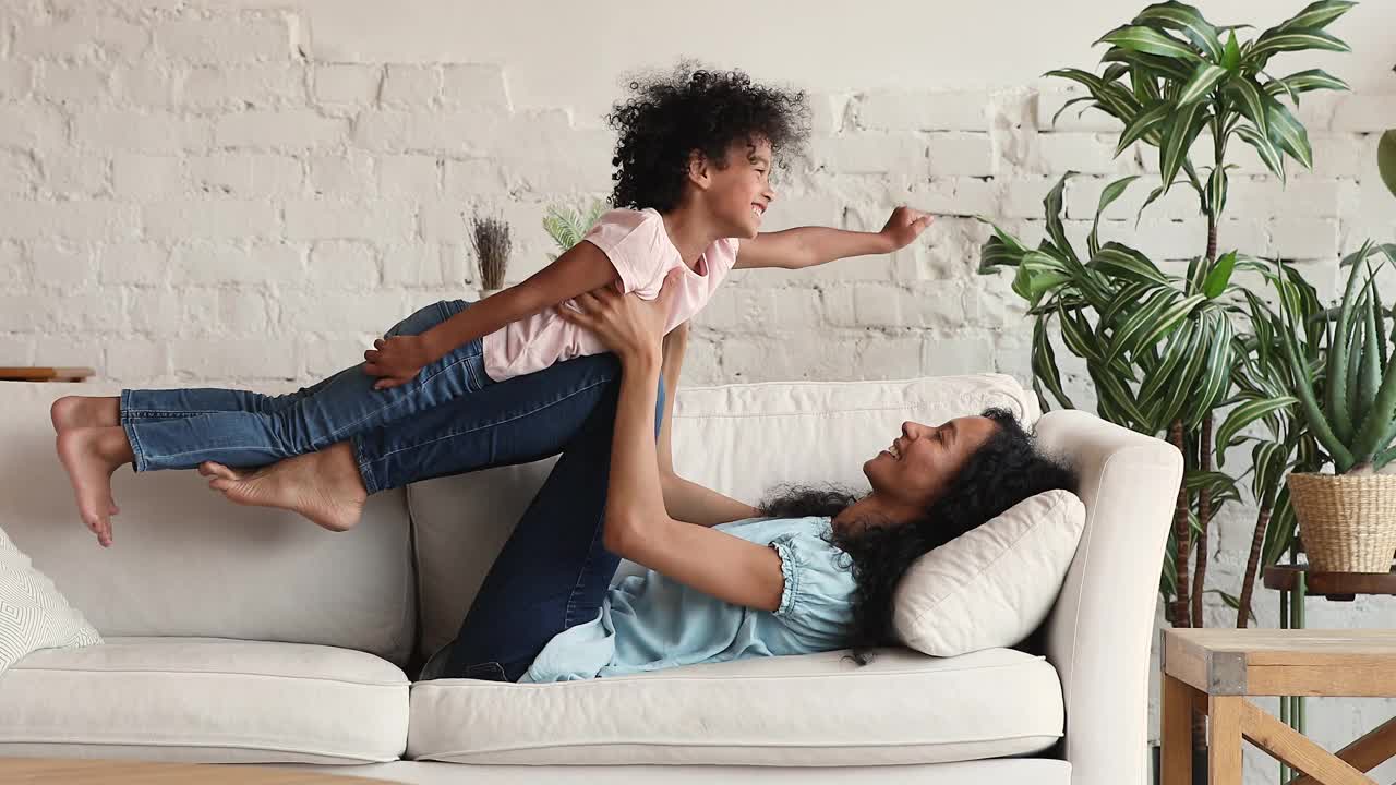 非洲母亲举起手臂，她的女儿喜欢在室内玩耍视频素材
