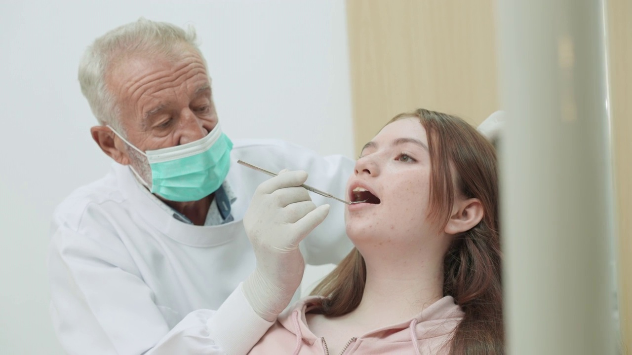 十几岁的女孩病人在老牙医的牙科检查，使用角度镜和牙科设备，手持侧视图视频素材