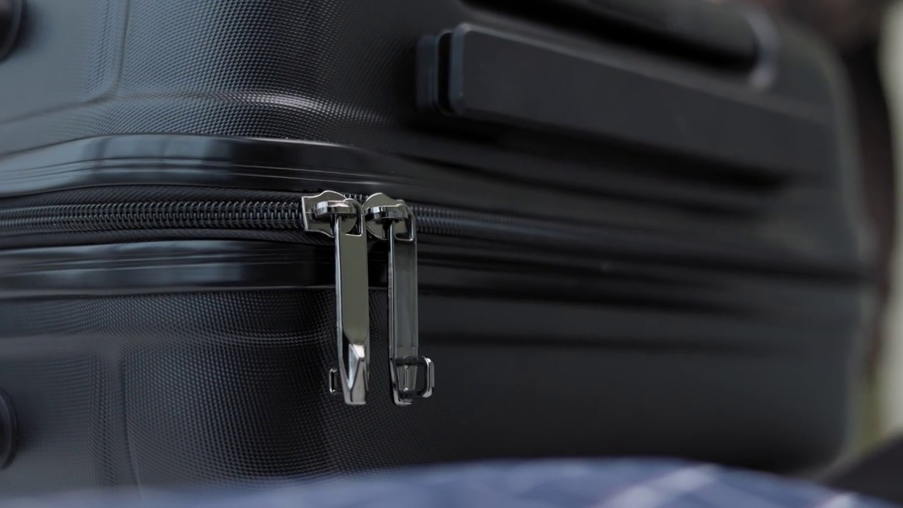 关闭男性手整理行李。手拉拉链关闭行李套件的箱子。在假期旅游度假时，为旅行打包。视频下载