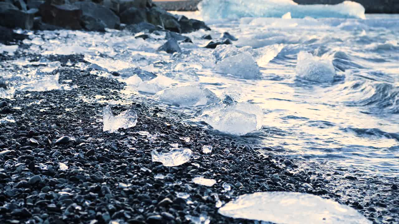 黑沙上的大块冰块，全球变暖气候变化概念，冰岛Jokulsarlon冰川泻湖的冰山视频下载