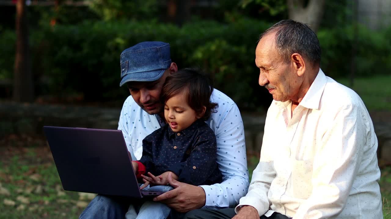 男人和孩子一起在公园户外使用笔记本电脑视频素材