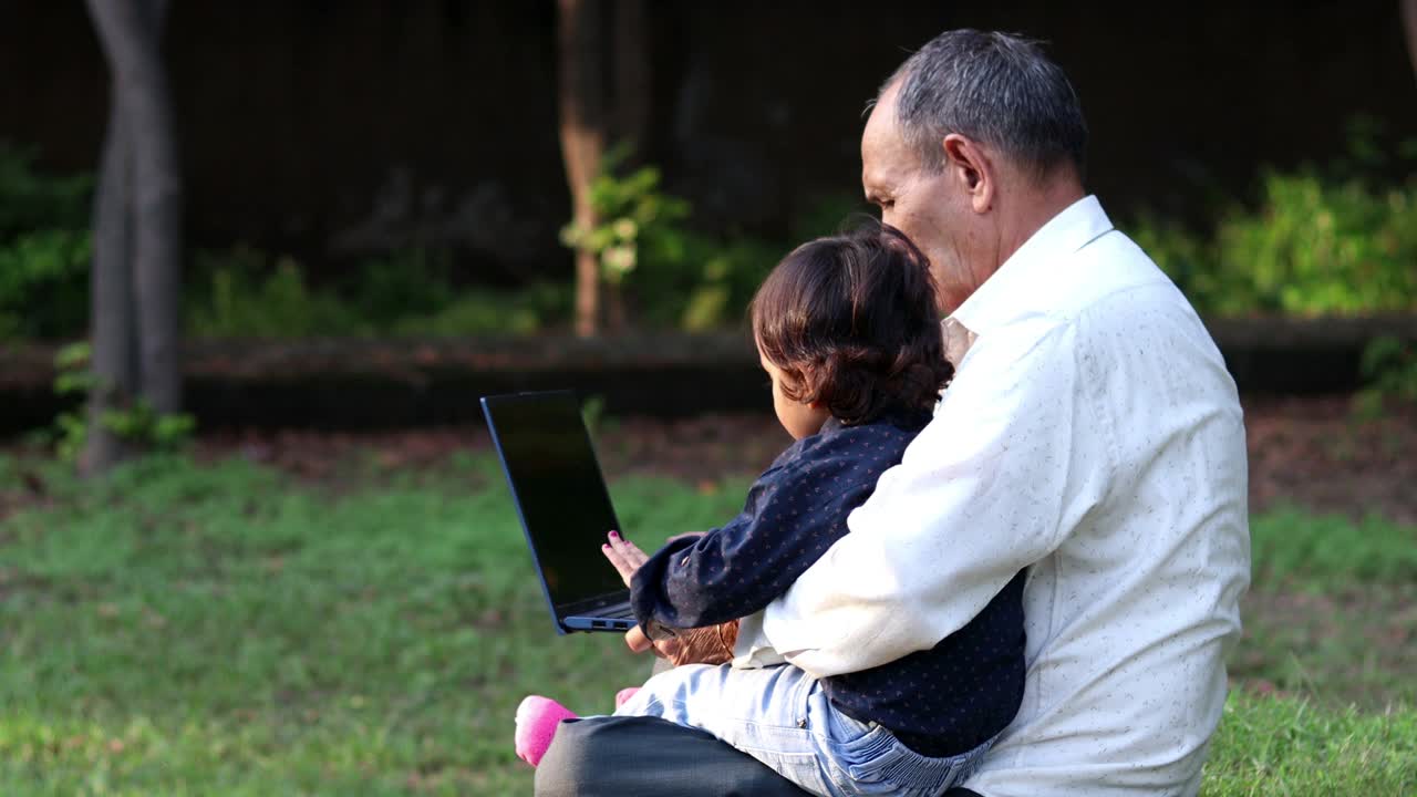 爷爷和小孩在公园里使用笔记本电脑视频素材