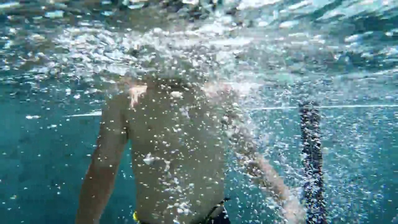 一个亚洲男孩在游泳池的水下玩耍和游泳视频素材