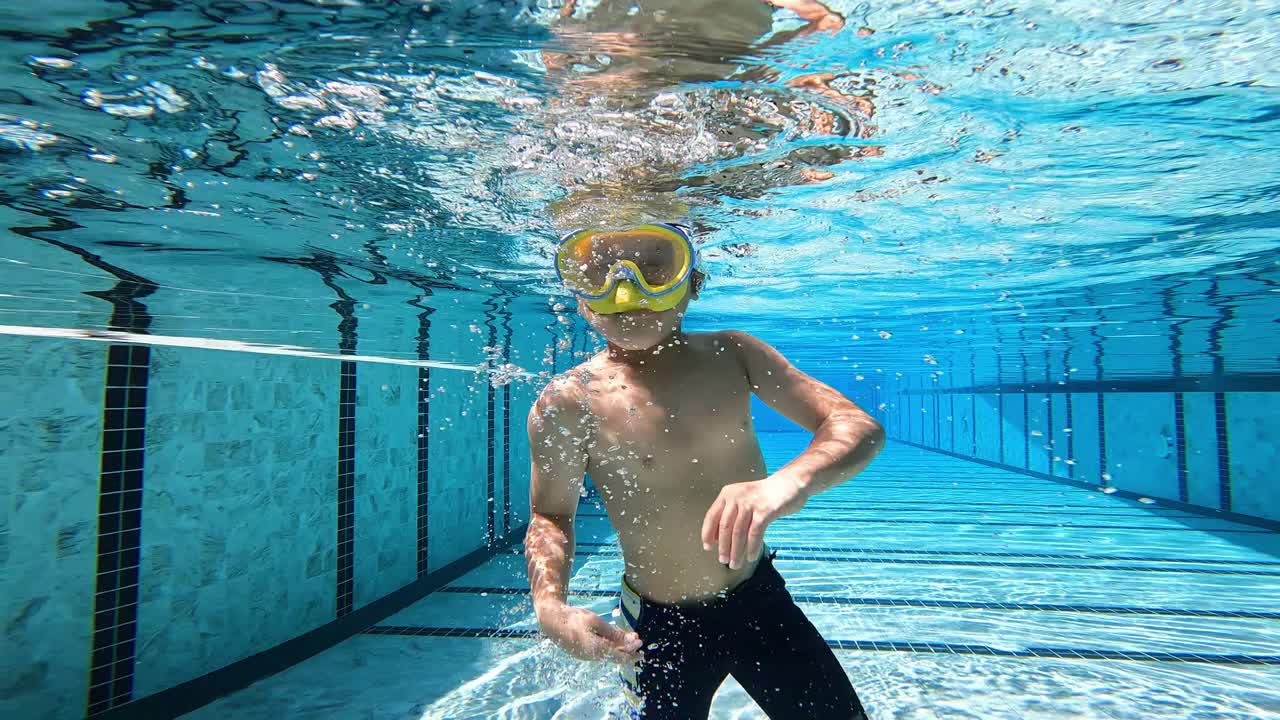 一个亚洲男孩在游泳池的水下玩耍和游泳视频素材