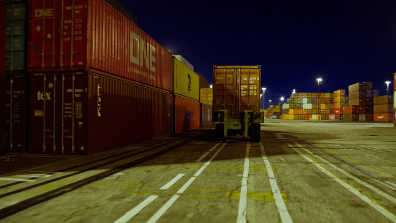 驾驶镜头跟随UTR在晚上经过成堆的集装箱视频下载