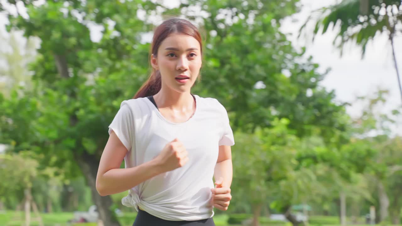 亚洲年轻美丽的运动女子在公园的街道上跑步。美丽的运动员和坚定的女孩在运动服装锻炼慢跑锻炼户外保健在傍晚日落在花园。视频素材