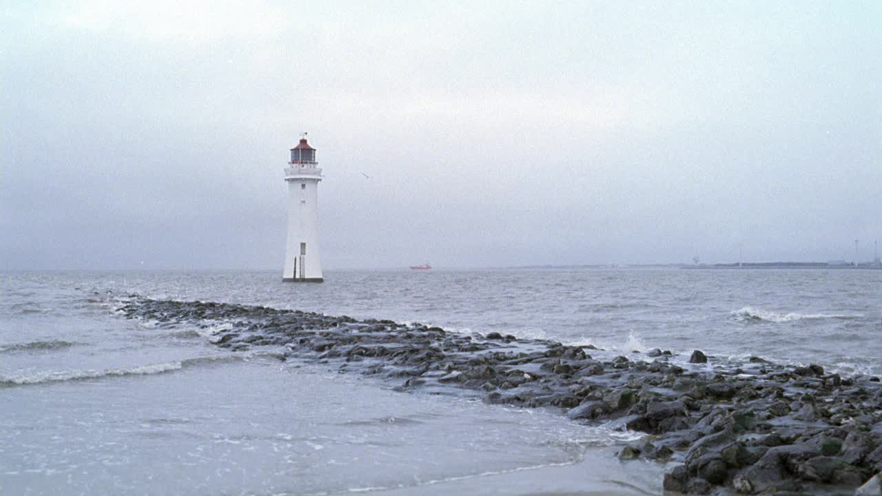 广角新布赖顿灯塔被大海或大海包围。见波浪撞击岩石或崎岖的码头和海岸线。天空有雾，阴天或多云。可能在东海岸。英格兰。海岸。视频素材