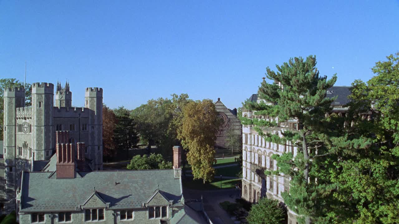 高角度下的布莱尔大厅和多层石或砖建筑在普林斯顿大学校园。镜头移到左边，看到人们，大学生走在院子里的小道上。树。学院的哥特式建筑。大学校园。视频素材