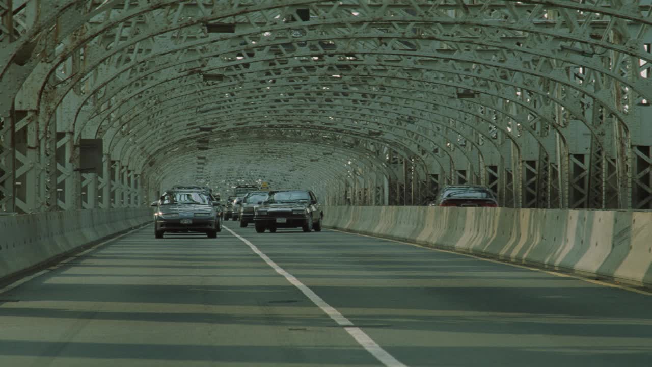 昆斯伯勒大桥上汽车驶向摄像机的广角镜头。土星sl2汽车或轿车打滑和突然停止引起交通堵塞。汽车开始四处行驶，停了车。关闭角度的汽车车轮和轮毂盖。附近的碰撞。视频下载