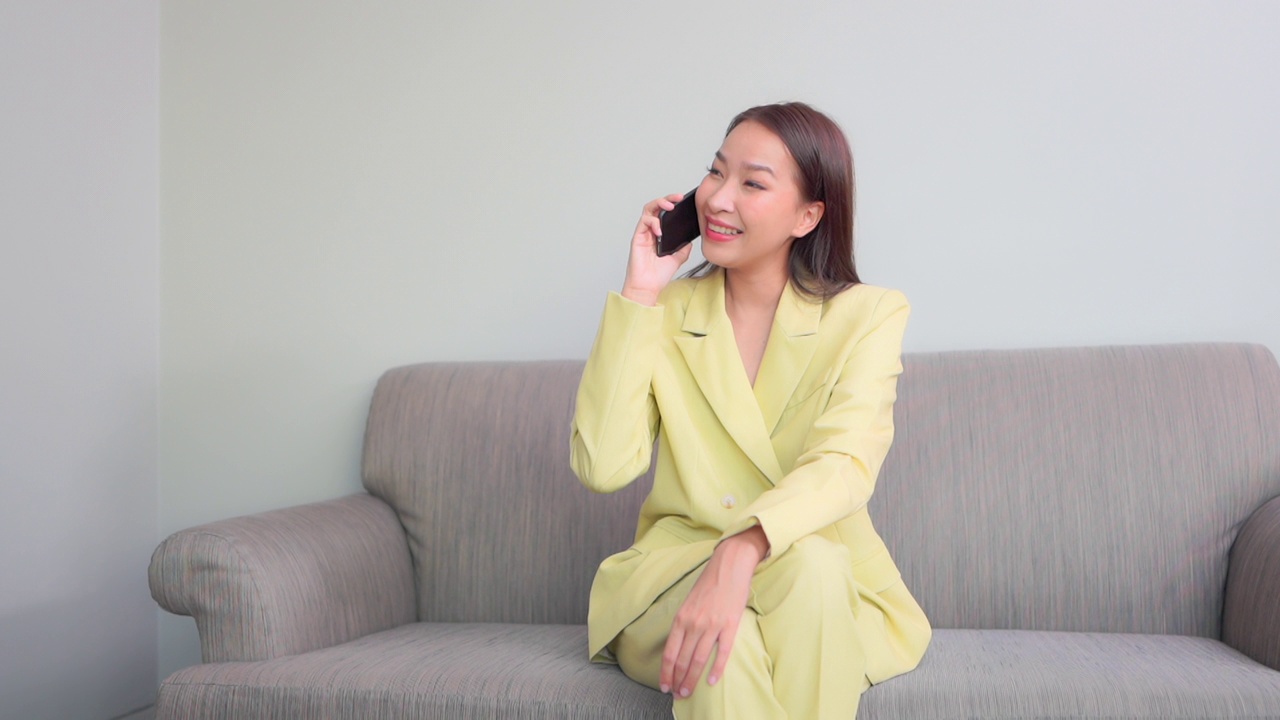 年轻的亚洲女性在床上使用智能手机视频下载