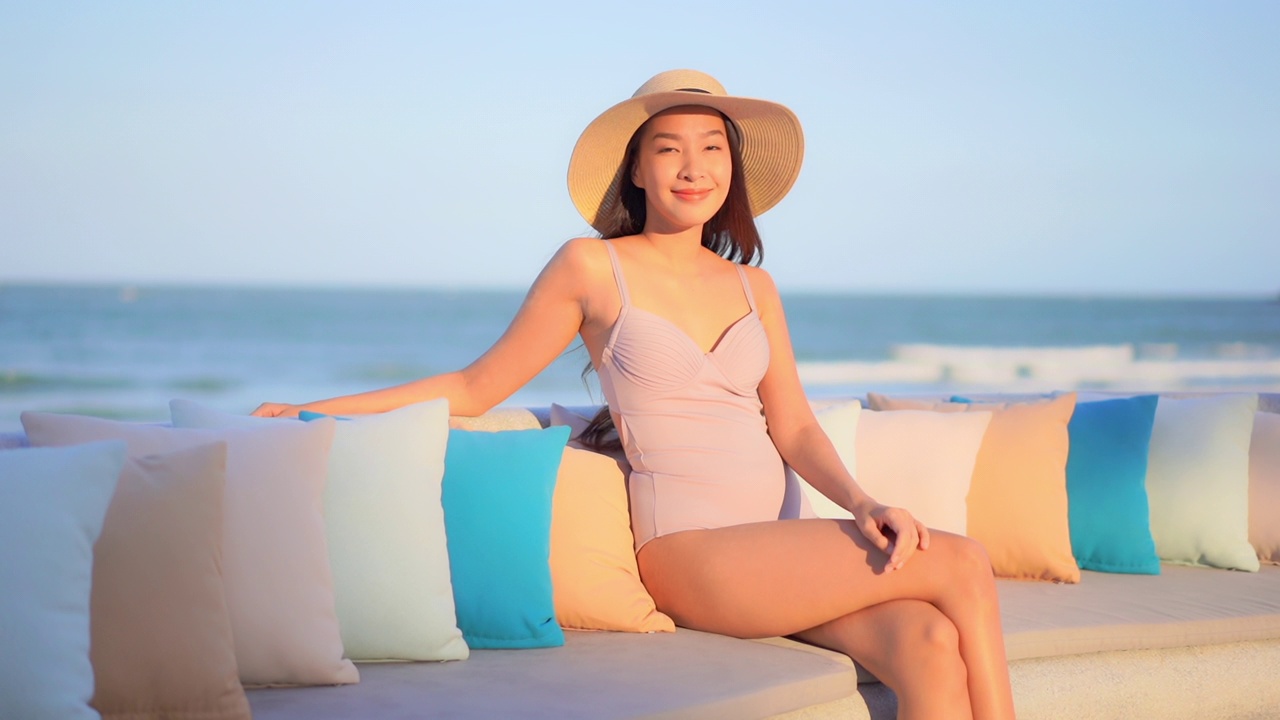 年轻的亚洲妇女快乐的微笑放松环顾四周的海，海滩，海洋视频下载